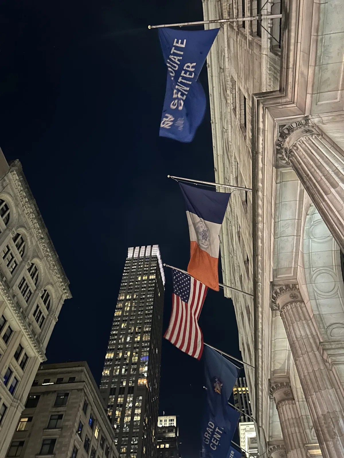 Flags outside the CUNY Graduate Center at night.
